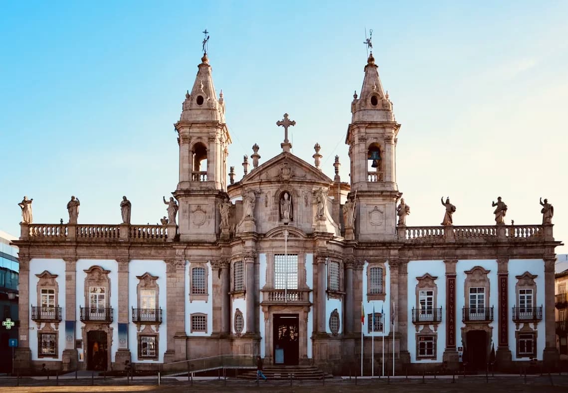 The majestic Baroque facade of the Braga Cathedral stands against a clear blue sky.