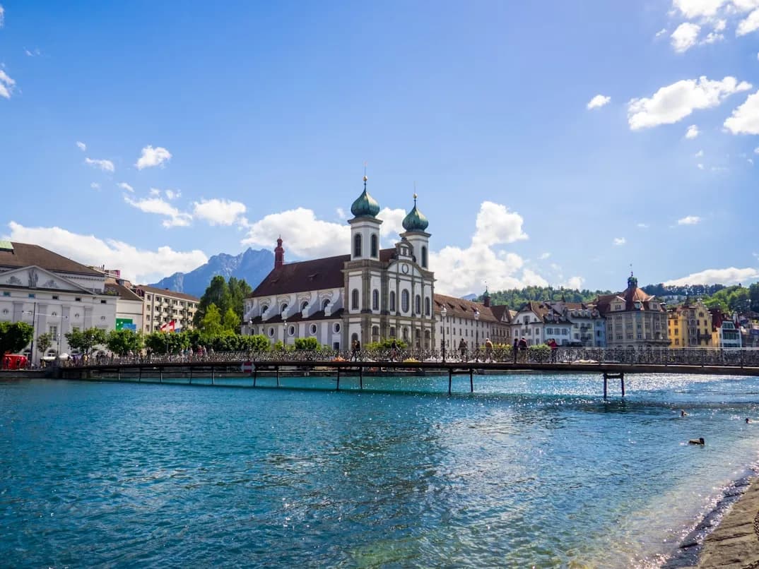 The magnificent Jesuit Church, with its baroque facade and twin green domes, stands on the banks of the Reuss River.