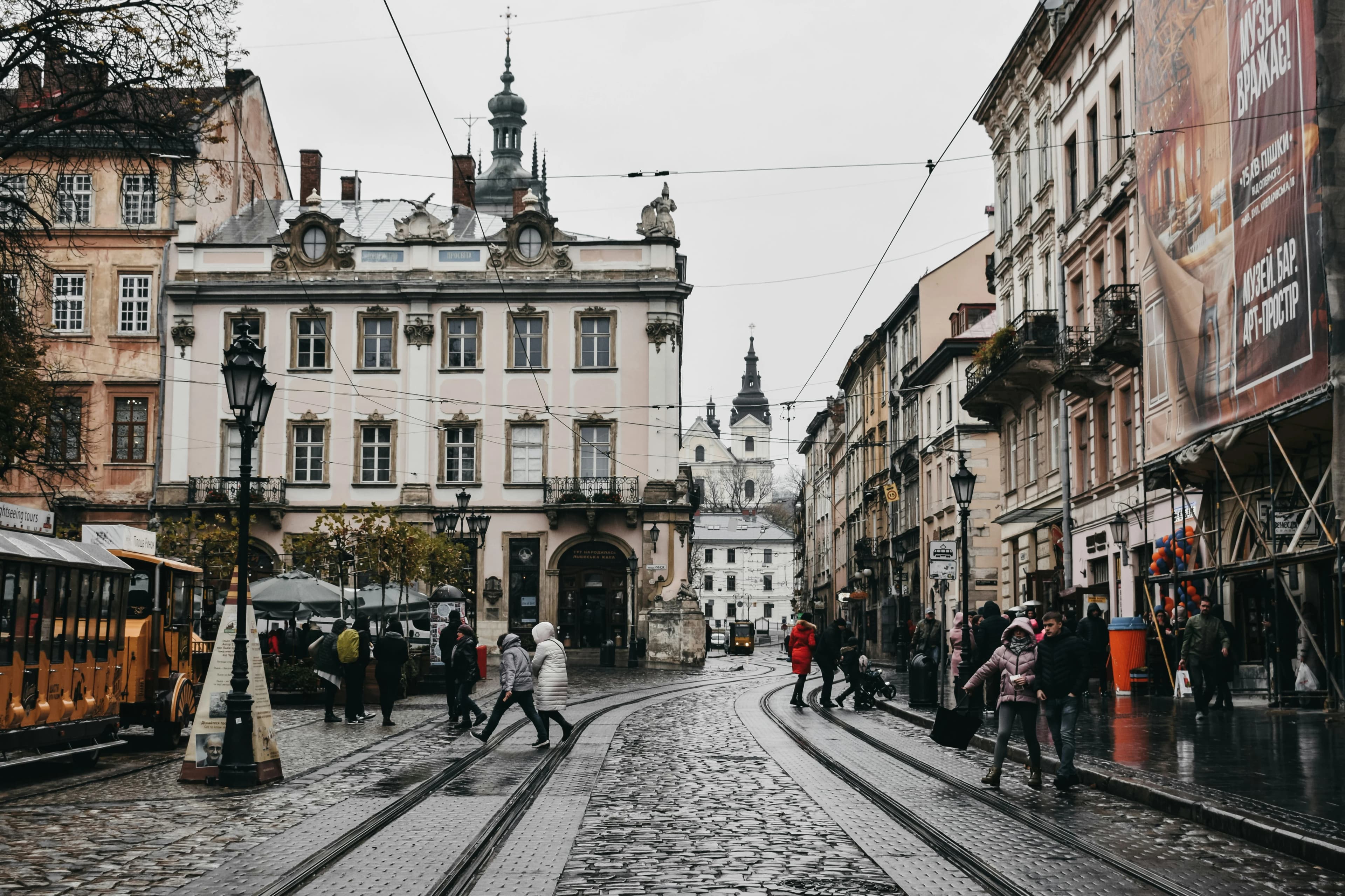 A bustling street scene in Lviv with people walking on cobblestone streets and vintage-style buildings lining the road.