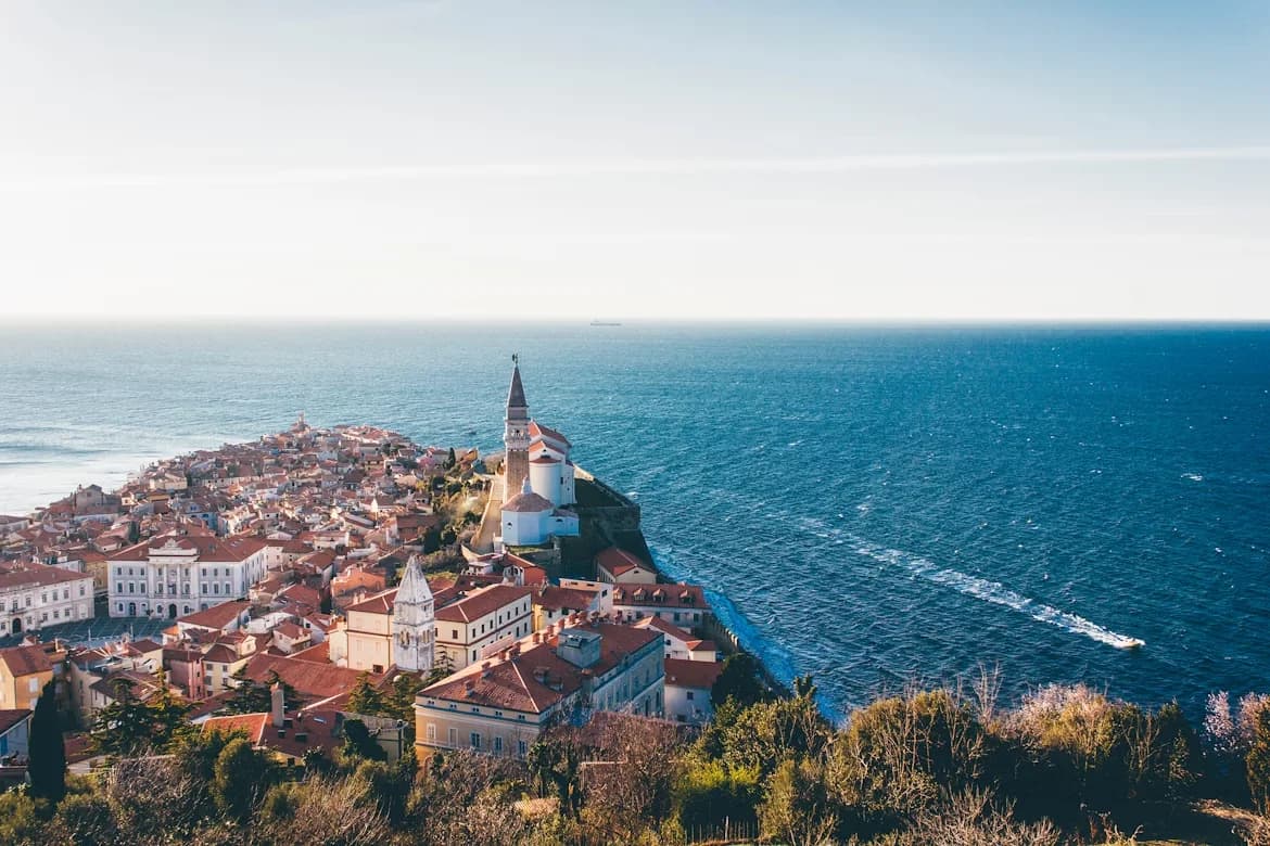The stunning town of Piran is built on a narrow peninsula, with its rooftops and bell tower overlooking the deep blue Adriatic Sea.