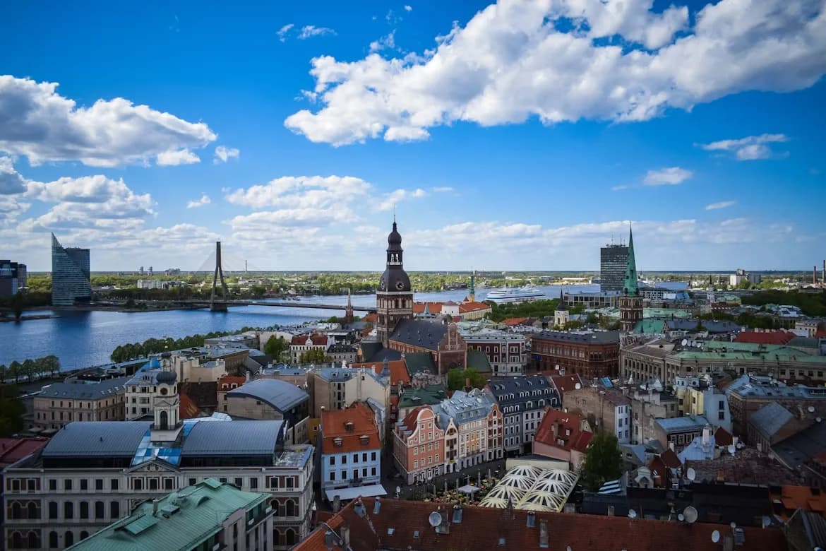 The skyline of Riga's Old Town, with the steeple of the Riga Cathedral and a modern bridge in the background, is a stunning sight on a clear day.