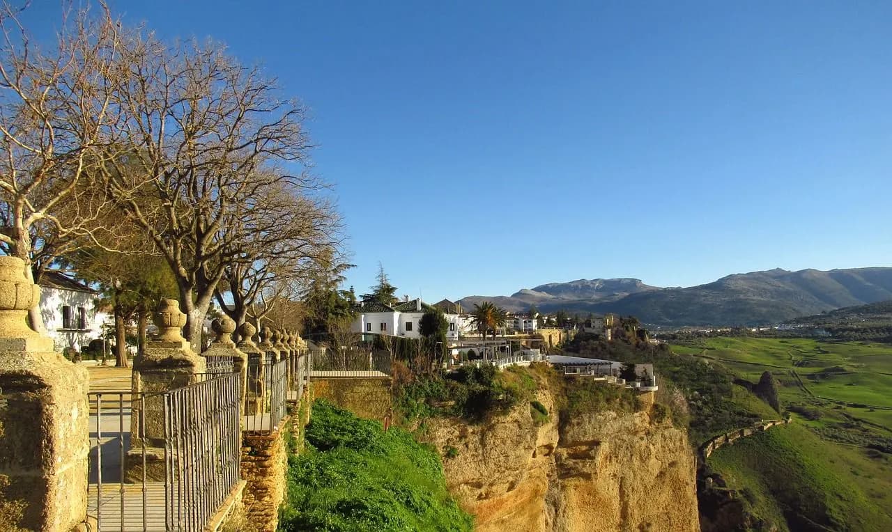 A scenic overlook with a stone balustrade provides a stunning view of the El Tajo gorge and the historic town of Ronda.