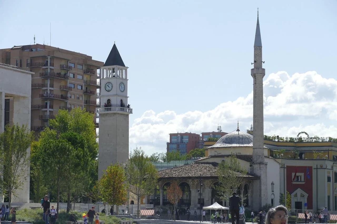 A tranquil, tree-lined path with benches on both sides offers a peaceful retreat in one of Tirana's many parks.