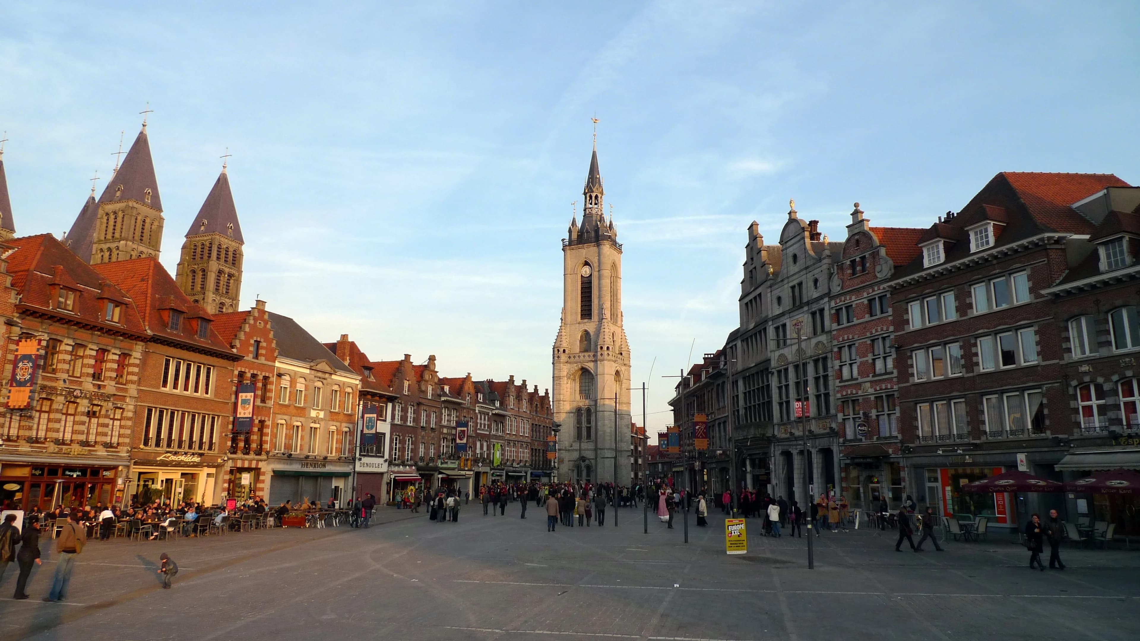 A scenic view of the River Scheldt, with the city's historic buildings and a modern bridge spanning the water.
