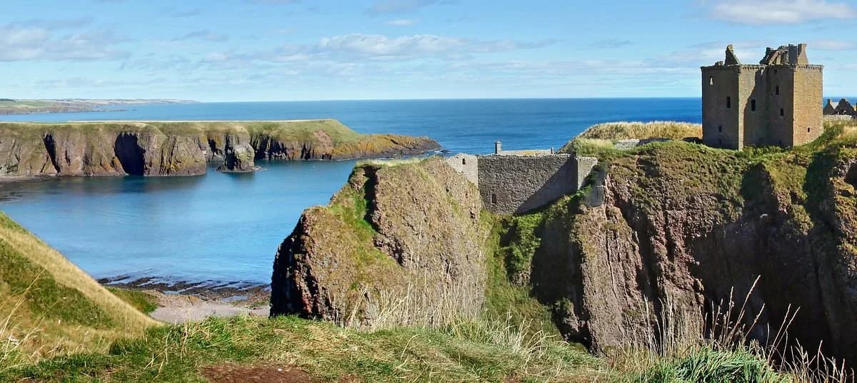 The ancient ruins of Dunnottar Castle stand on a dramatic cliff overlooking a quiet bay and the North Sea.