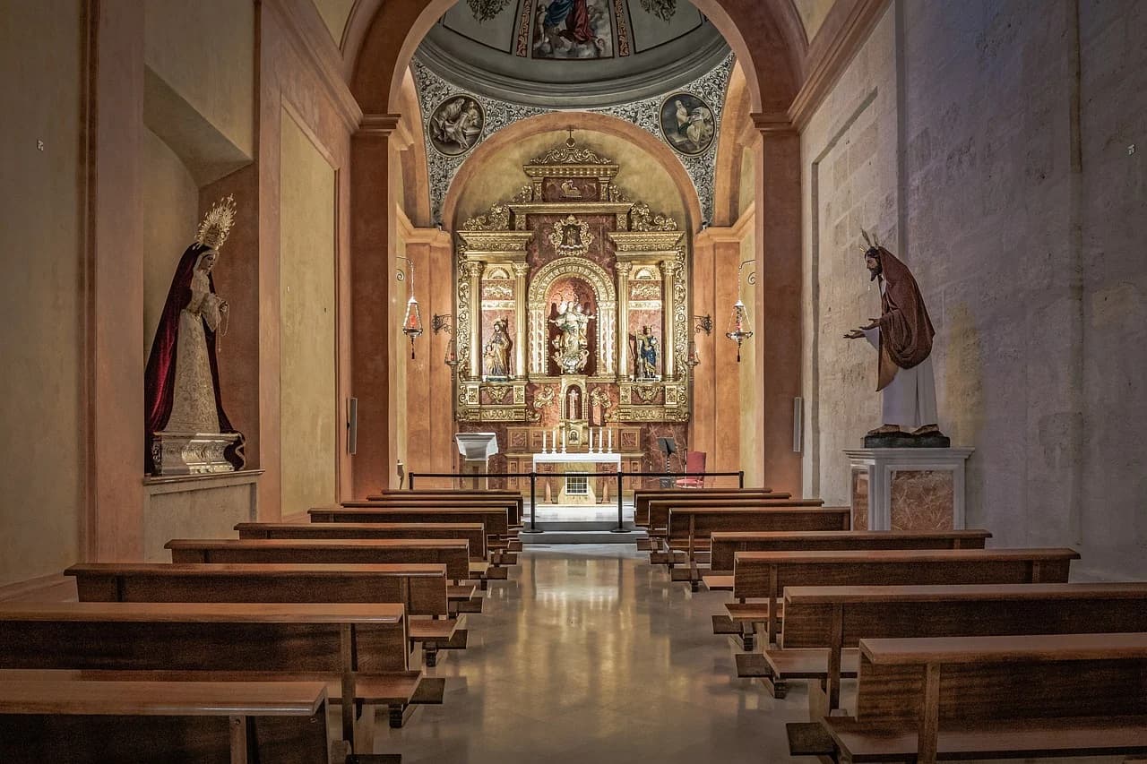 A quiet church interior with rows of empty pews and a large, ornate altar at the far end.