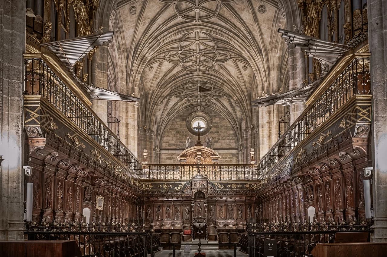 The grand, intricate interior of a choir stall in a historic church, with a large pipe organ and a high, vaulted ceiling.