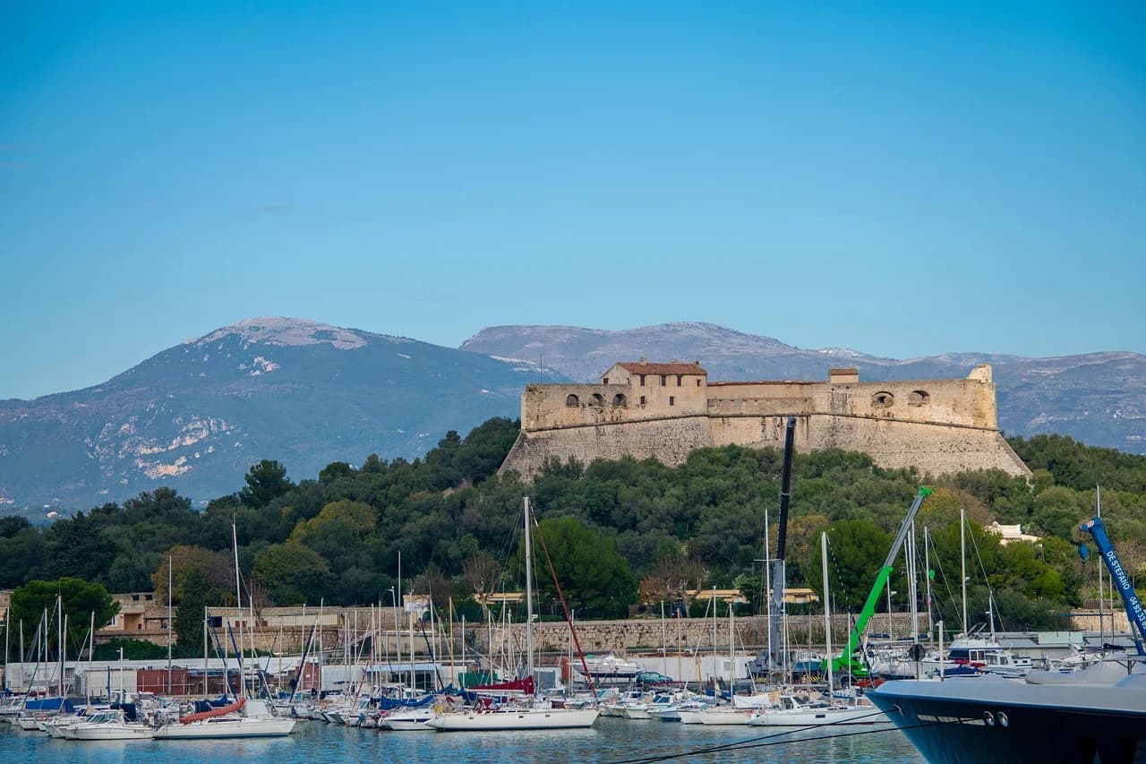 The historic Fort Carré sits on a green hillside overlooking the harbor of Antibes, with numerous sailboats moored below.