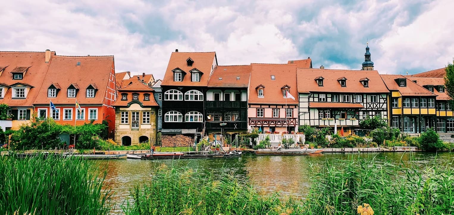 The iconic Altes Rathaus, a historic town hall built on a bridge in Bamberg, is surrounded by a beautiful waterway and is a testament to the city's unique charm.