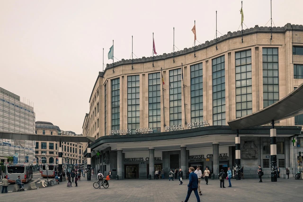 The grand facade of the Brussels Central Station is a prominent feature of the city, with people bustling in the square below.