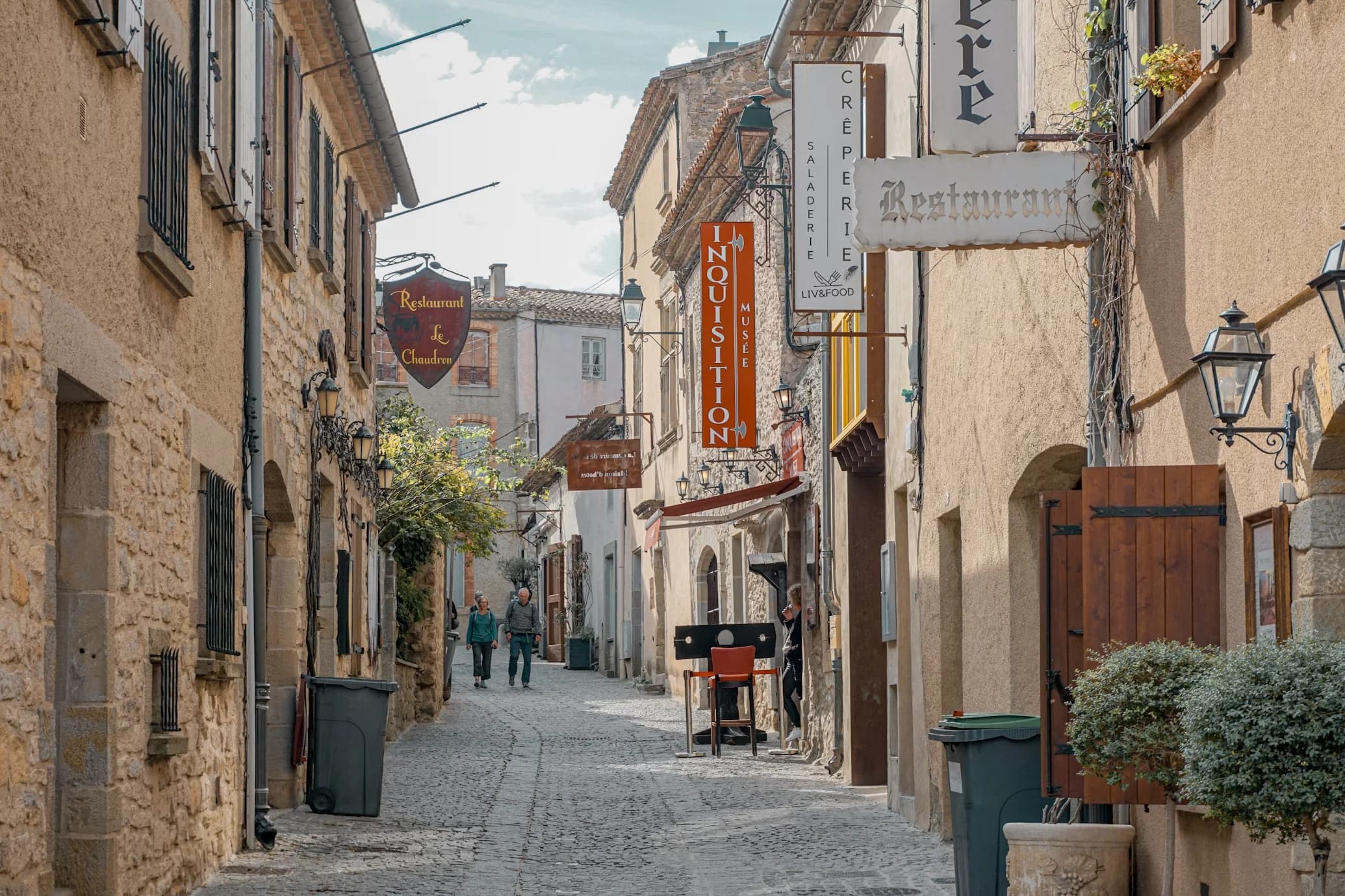 A narrow, cobblestone alleyway in the historic city of Carcassonne is lined with stone buildings and small shops.