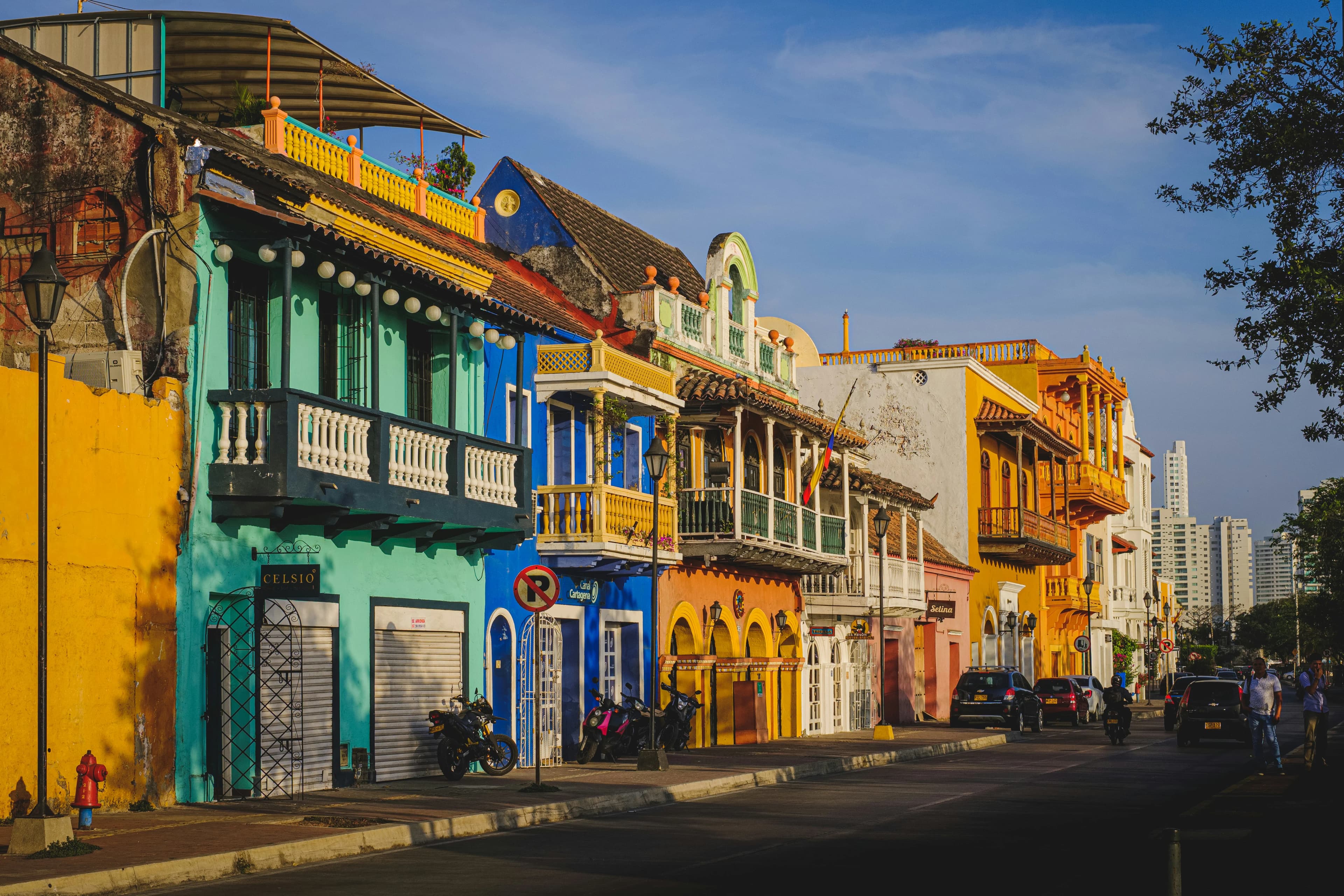 A vibrant street in the Old Town of Cartagena is lined with colorful buildings featuring traditional wooden balconies.