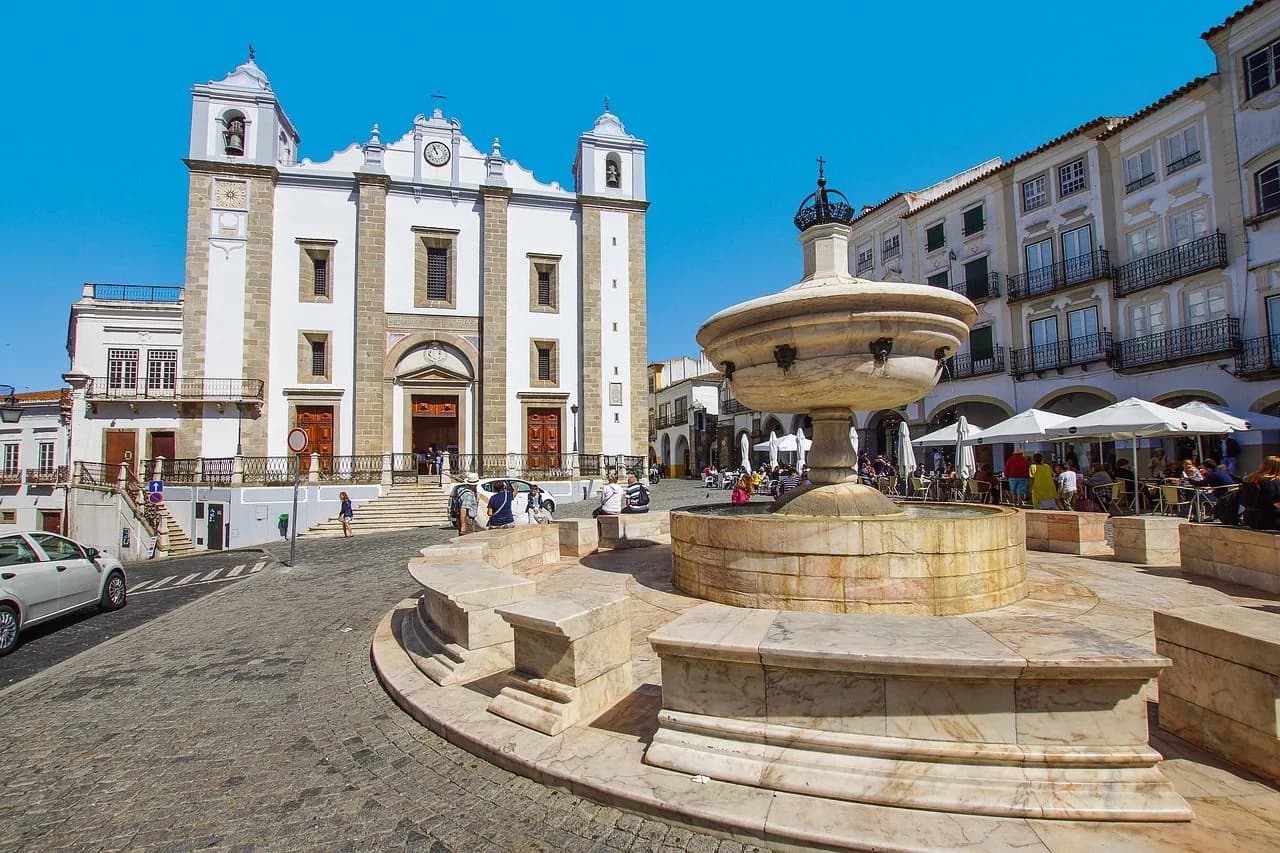 The main square of Évora, Praça do Giraldo, featuring a large marble fountain and a white church.