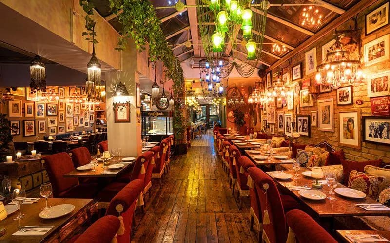 A bustling harbor is filled with numerous fishing boats, with the historic city and a lighthouse on the pier.