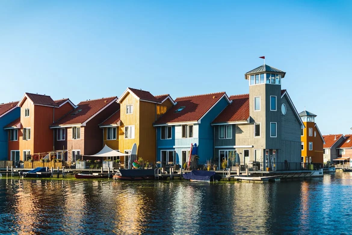 A scenic canal in Groningen is lined with traditional Dutch houses, with a few small boats moored on the water.