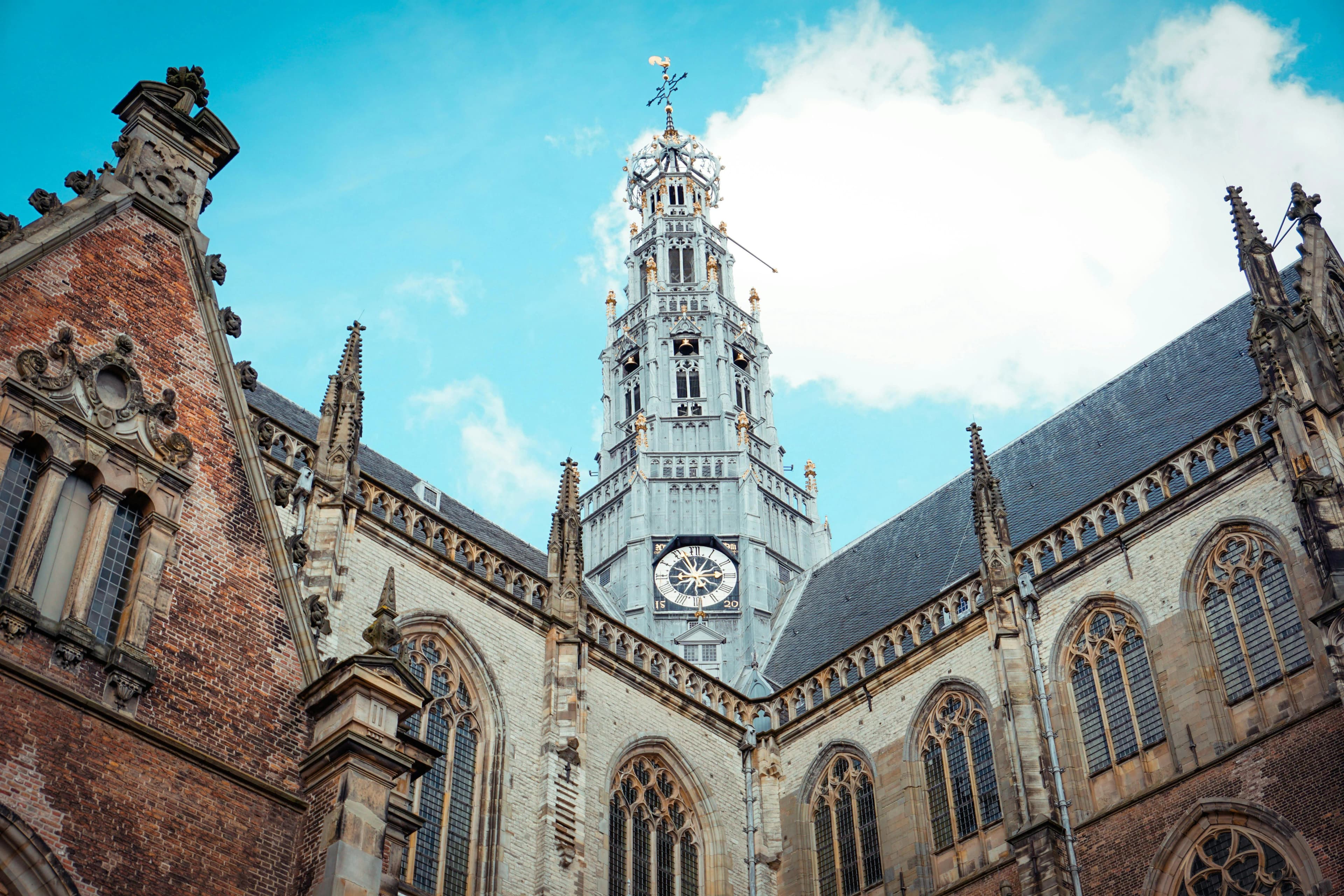 A low-angle view captures the soaring belfry and intricate stonework of the Grote Kerk, a masterpiece of Gothic architecture.