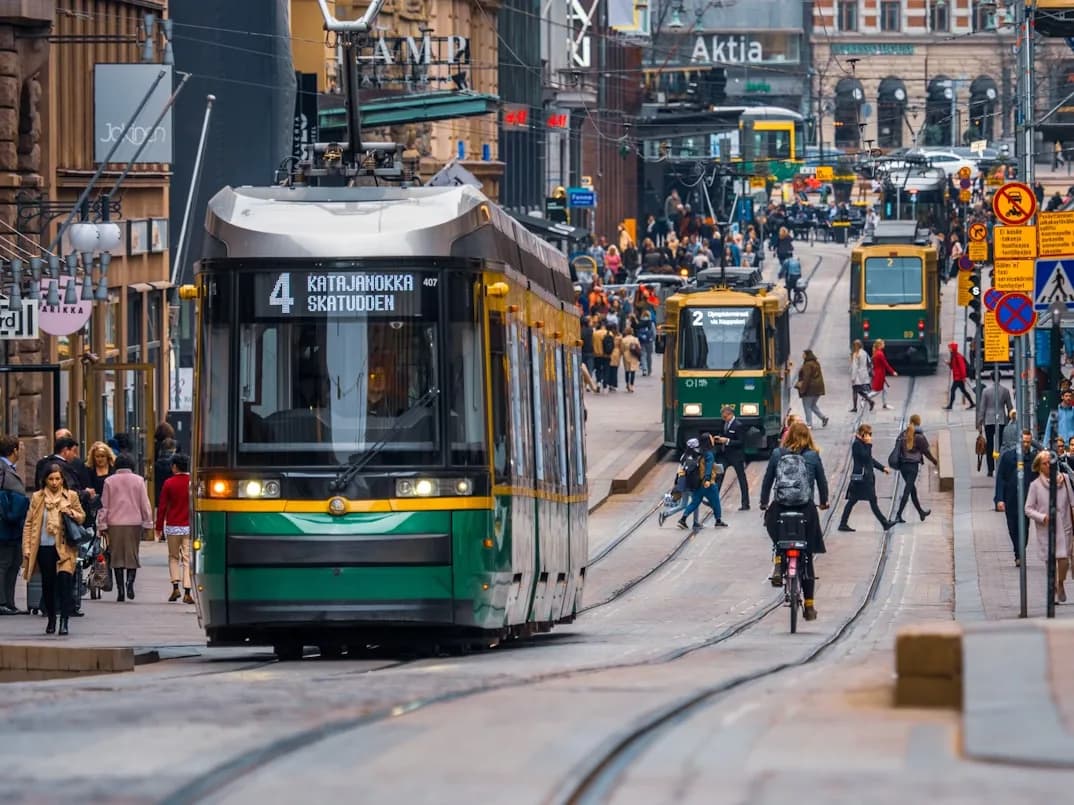 Trams and people fill a busy street in Helsinki, showcasing the city's lively and efficient public transport system.