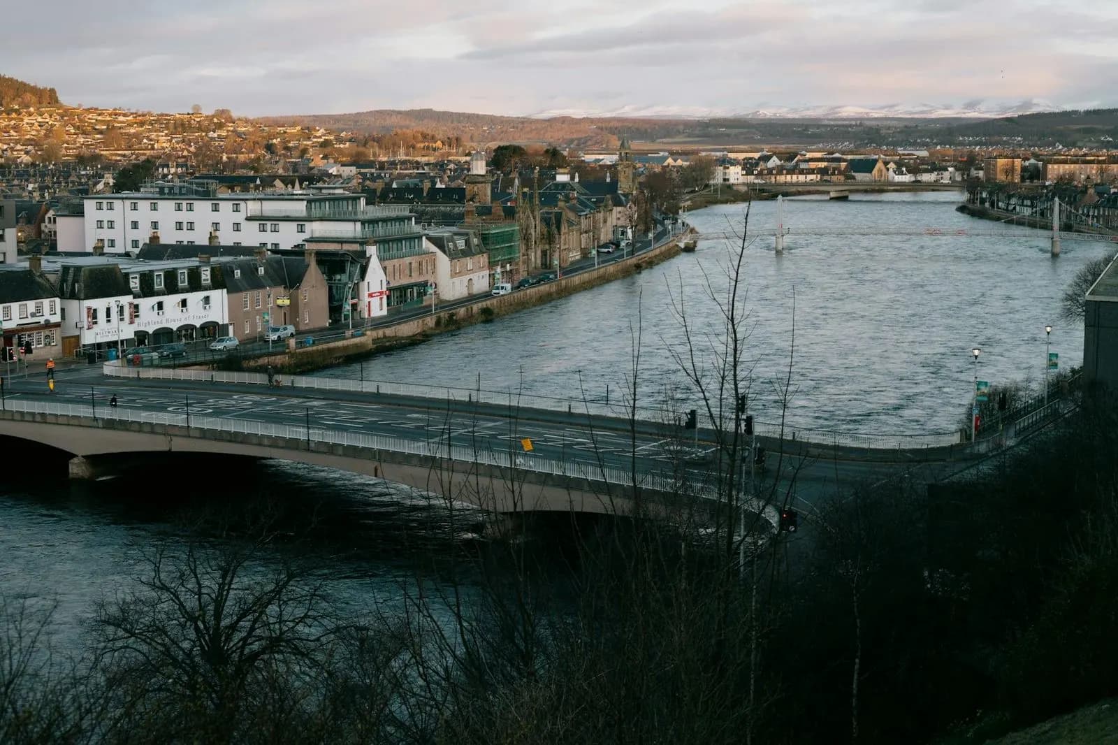 The tranquil River Ness flows through the city of Inverness, with bridges connecting the historic streets and buildings on both sides.