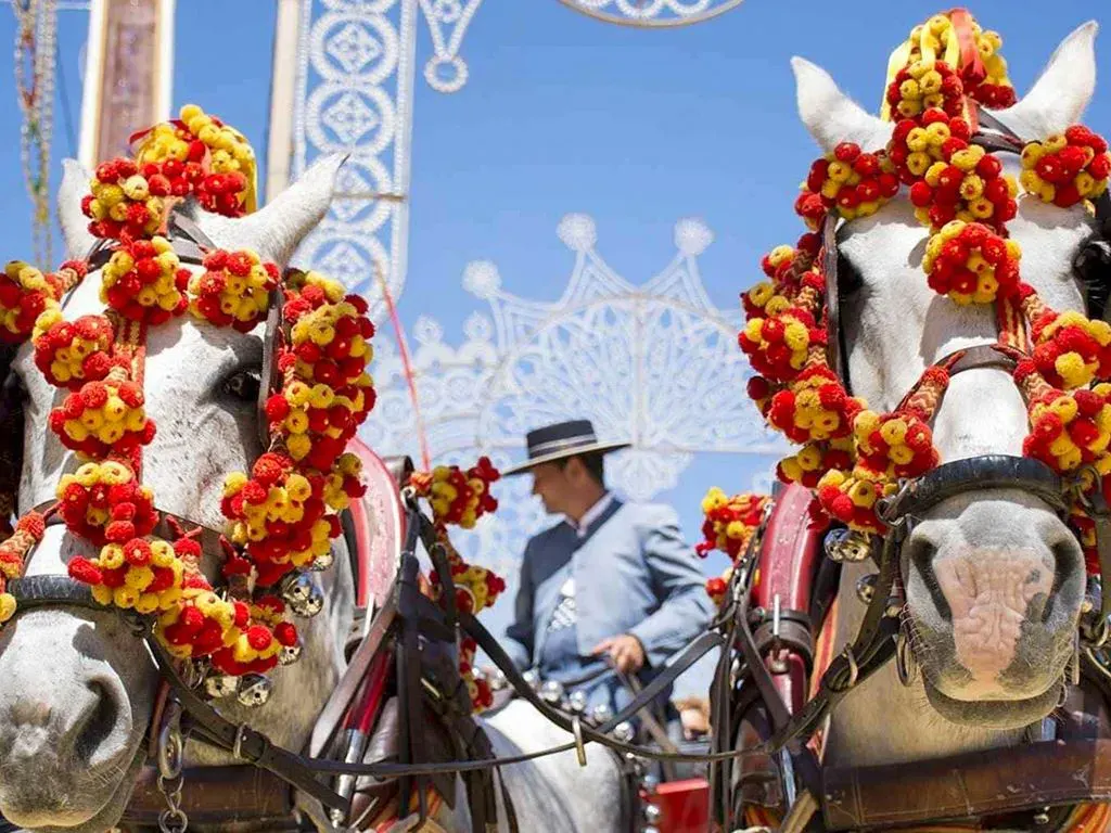 Two beautifully decorated white horses pulling a carriage are a highlight of a festival in Jerez de la Frontera.