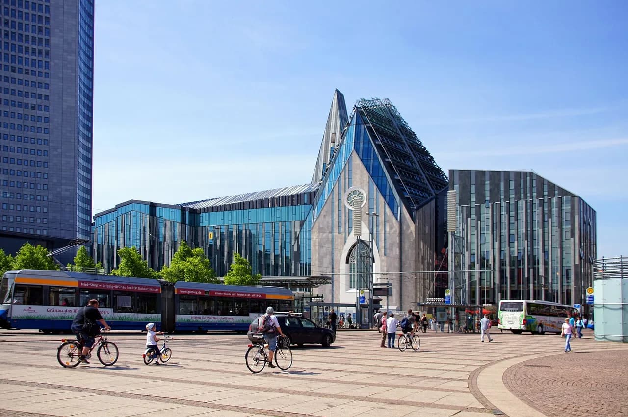 The stunning, modern glass facade of the Leipzig University building is a contemporary landmark on a busy city square.