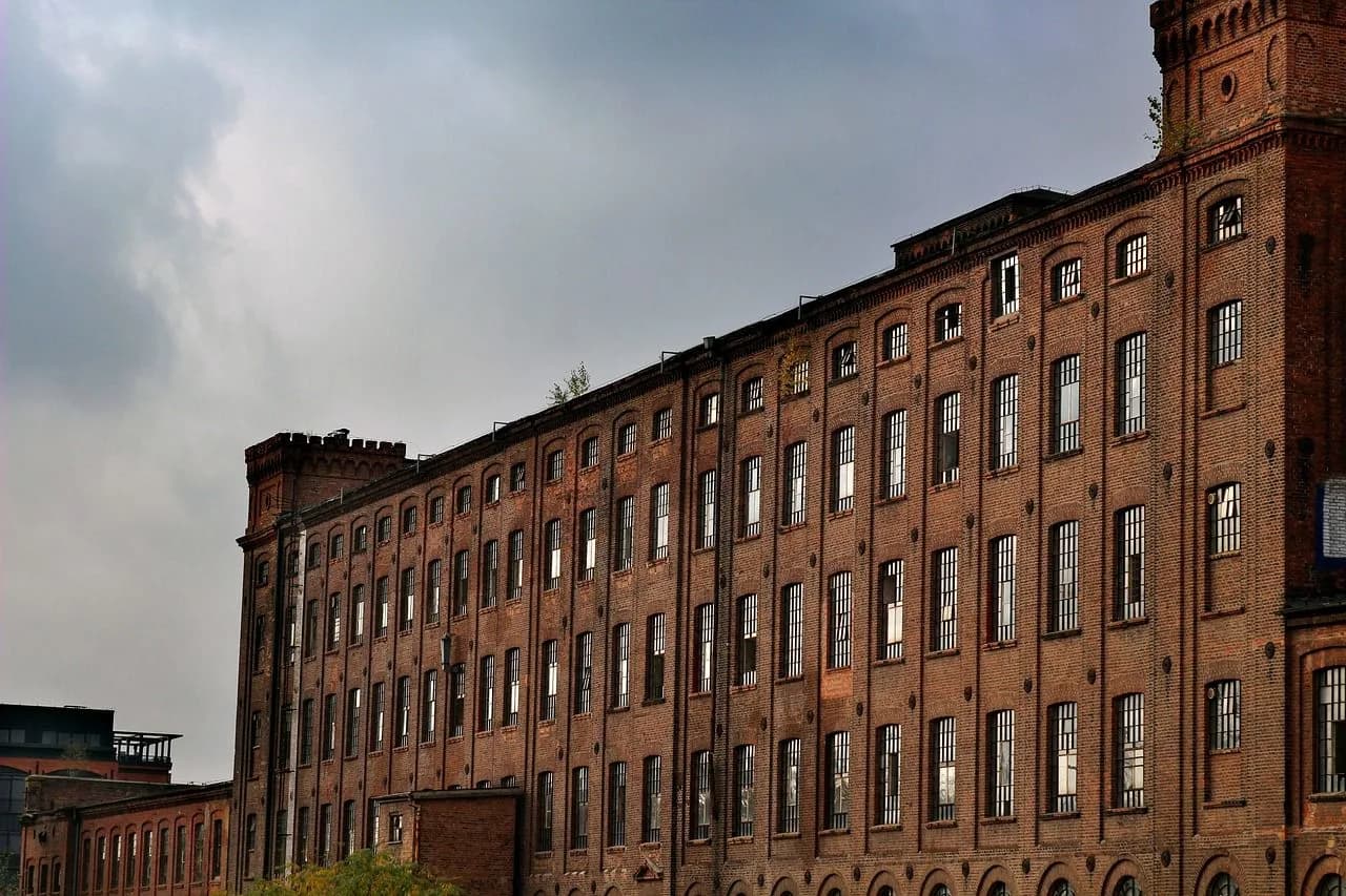 The large, red brick facade of a historic textile factory is a testament to the city's industrial past.
