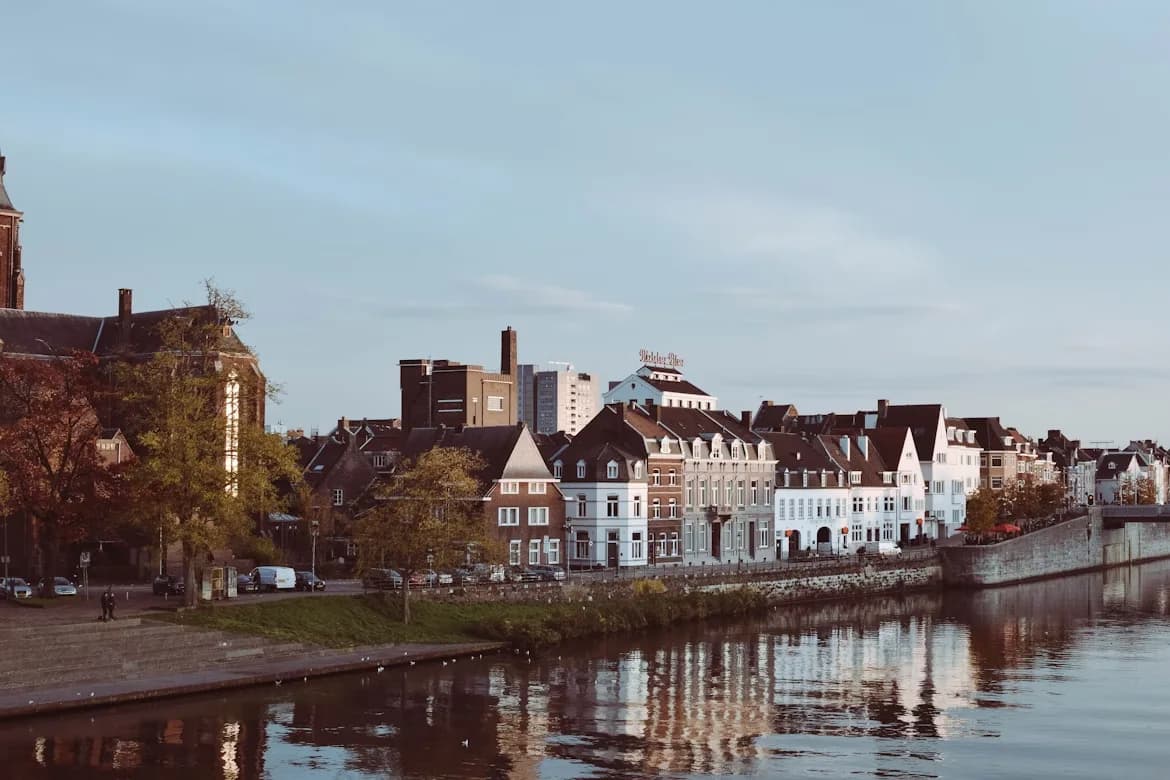 A large, historic square in Maastricht is bustling with people, cafes, and shops.