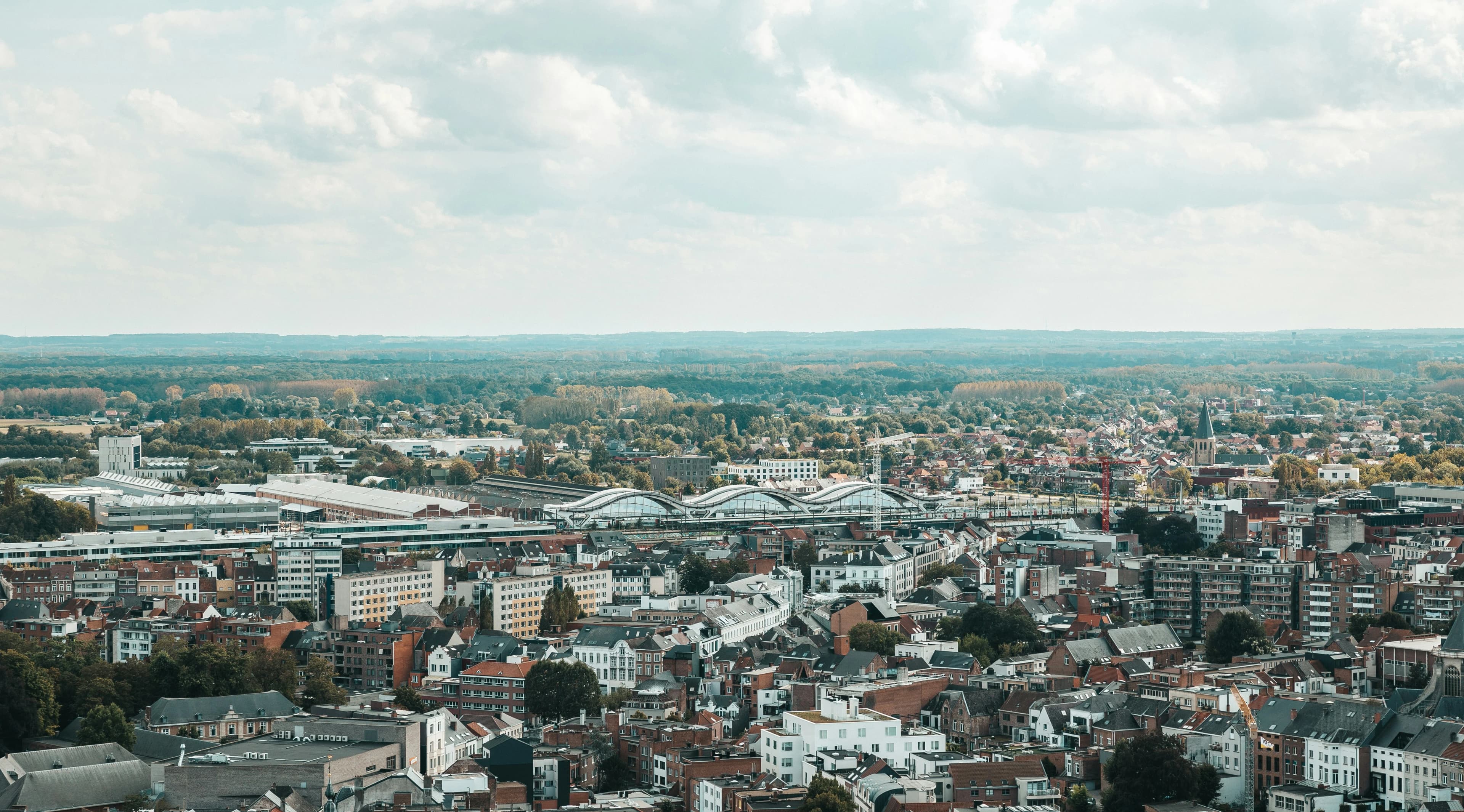 An aerial view captures the city of Mechelen, with its large church and dense residential buildings.