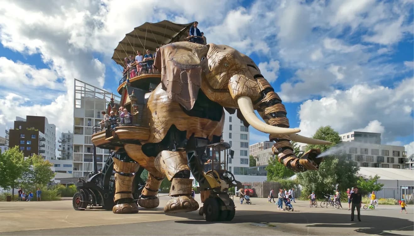 A large, mechanical elephant with people riding on top of it is a unique sight in a city square.