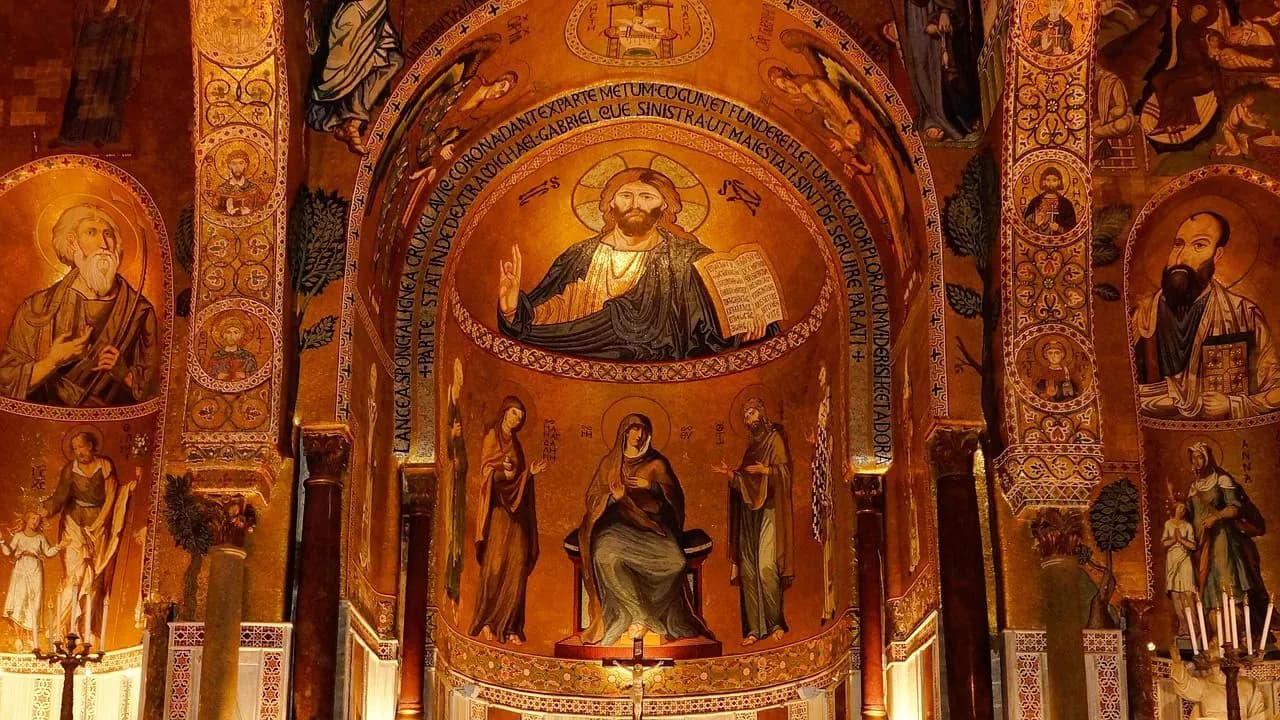 The ornate, golden interior of a historic chapel features intricate mosaics of religious figures and biblical scenes.