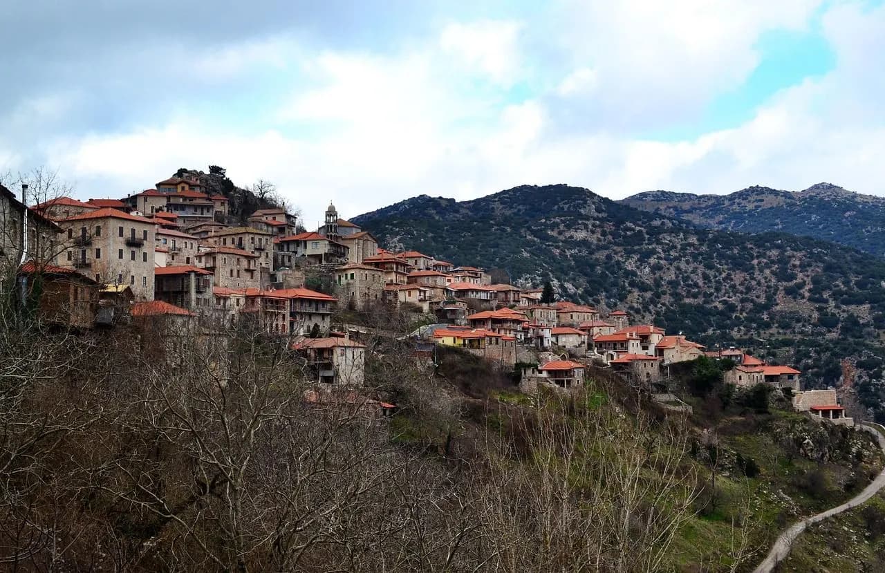 The fortified medieval town of Monemvasia, with its stone buildings and red rooftops, is built into a rocky hillside.