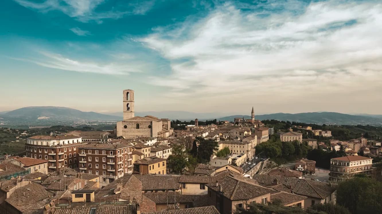 An aerial view of Perugia shows the dense, historic rooftops and the city's landmarks nestled in the hills.