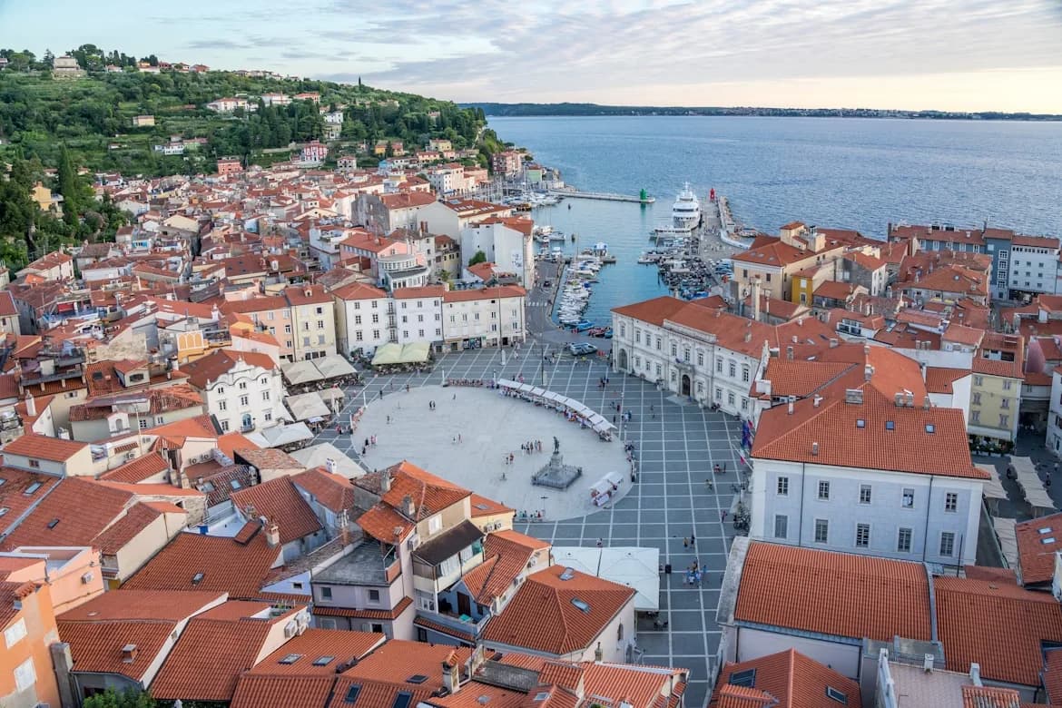 An aerial view captures the charming town of Piran, with its red-tiled roofs and the sea surrounding it on three sides.