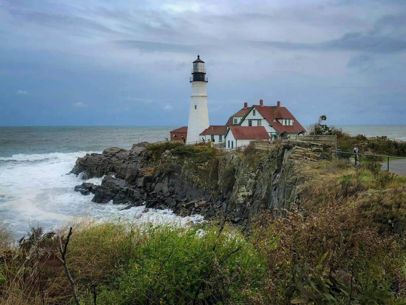 The historic Portland Head Light, a picturesque lighthouse, stands on a rugged, rocky cliff overlooking the Atlantic Ocean.
