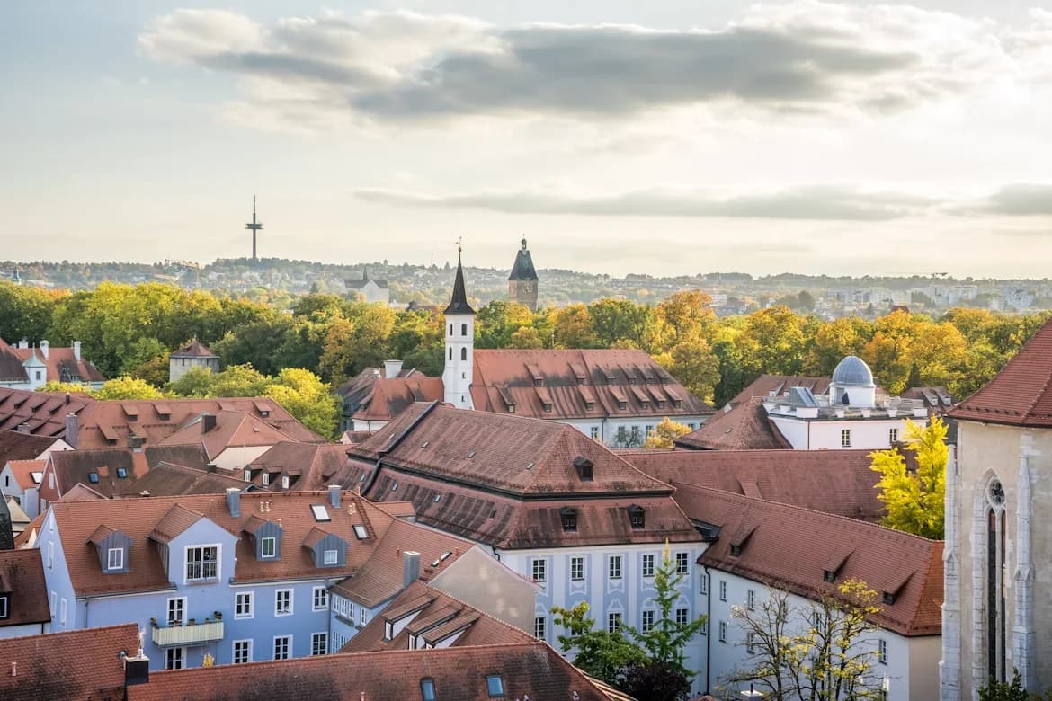 A panoramic view of the Regensburg skyline shows a mix of historic red-tiled roofs and modern buildings.
