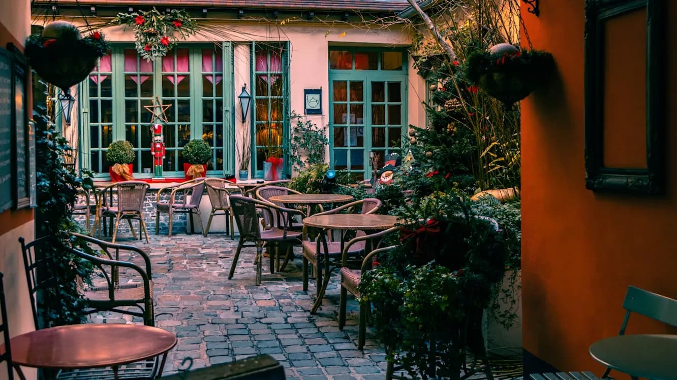 The cozy and charming interior of a festive restaurant with an outdoor courtyard, decorated with plants and lanterns.