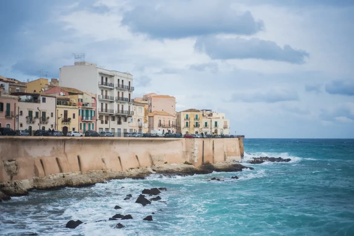 A historic fountain with statues of mythical creatures and a horse is the centerpiece of the Piazza Archimede in Ortigia.