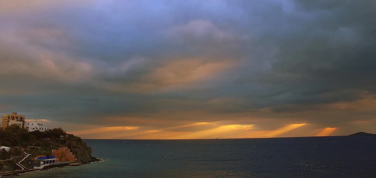 The historic buildings of Ermoupoli are illuminated at dusk, with the lights of the city and the harbor glowing.