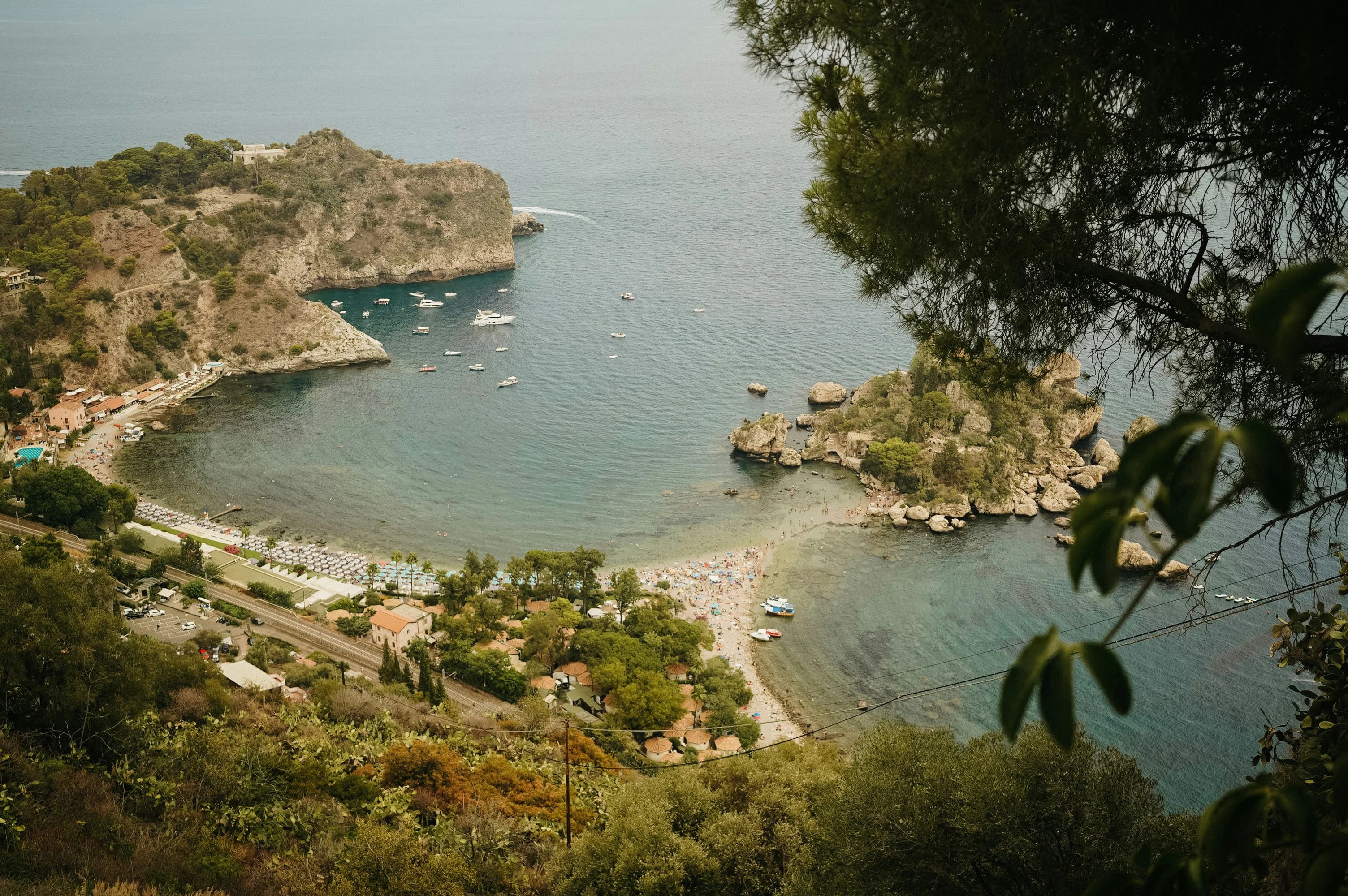 A long, narrow swimming pool with an infinity edge offers a stunning view of the sea and the surrounding hills.