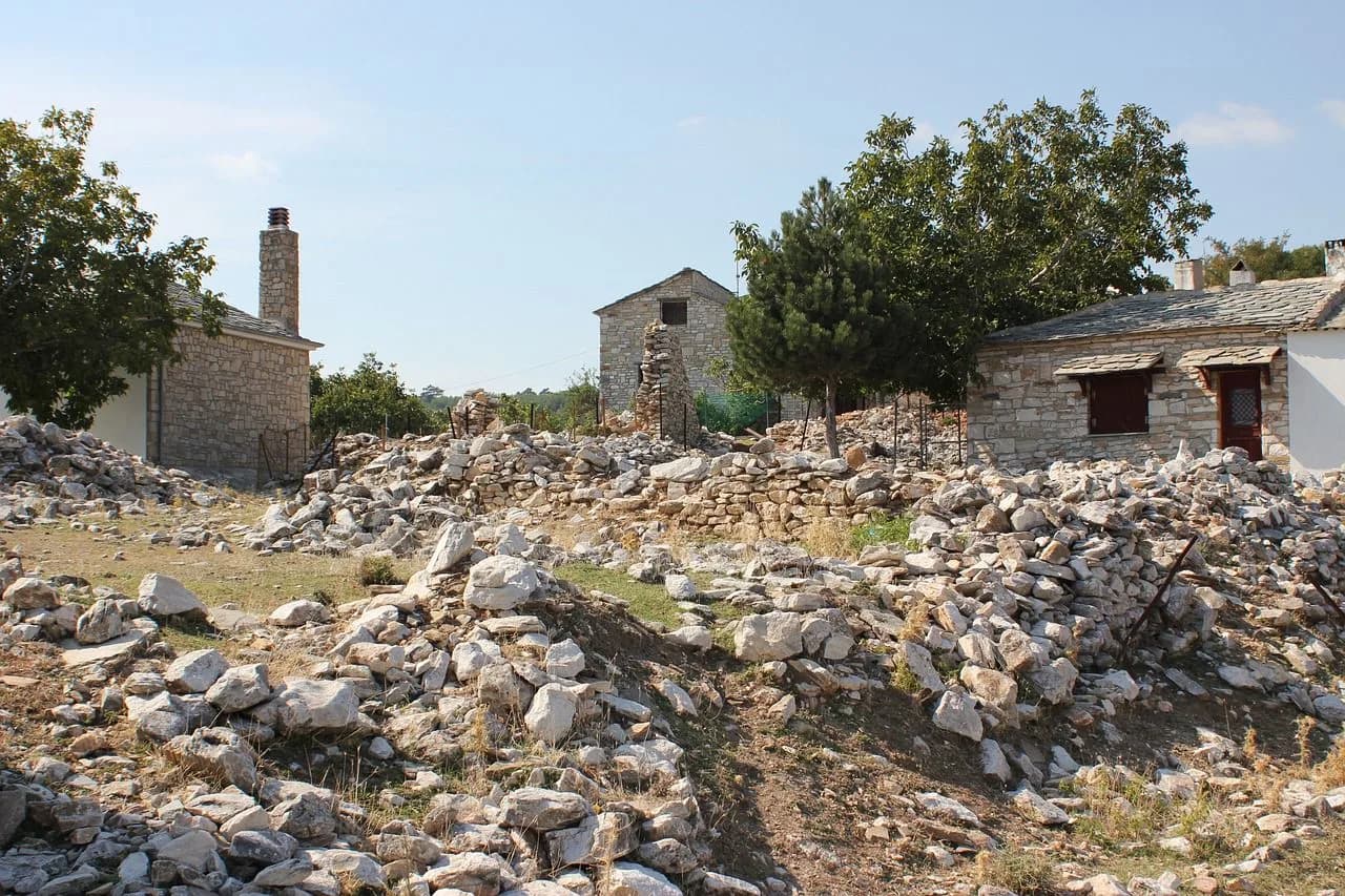 A small, white Greek Orthodox chapel is nestled on a rocky cliff overlooking the Aegean Sea.