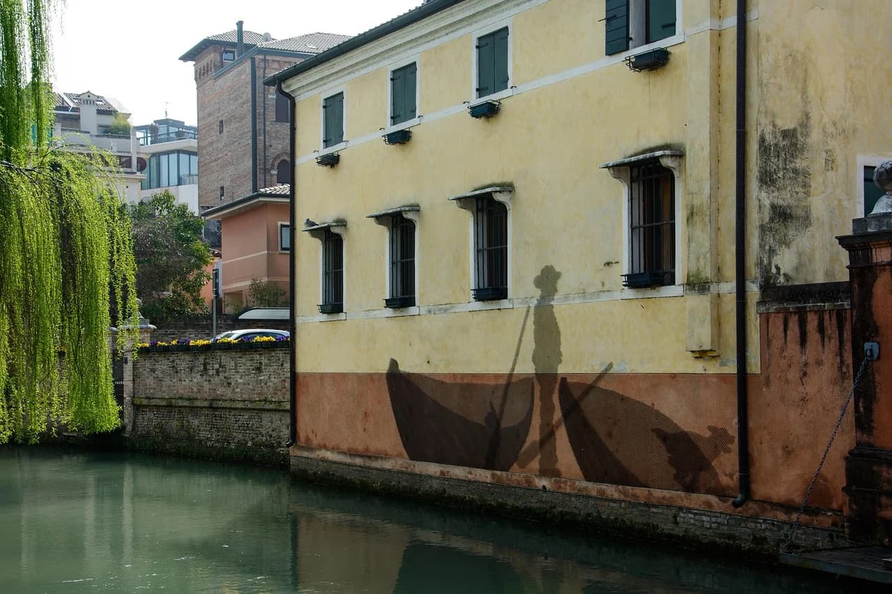 A narrow, picturesque street in Treviso is lined with historic buildings and cafes with outdoor seating.