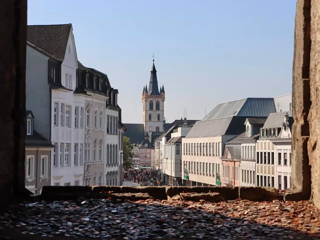 The Aula Palatina, a large Roman hall with a basilica-like structure, stands in the center of a city square.