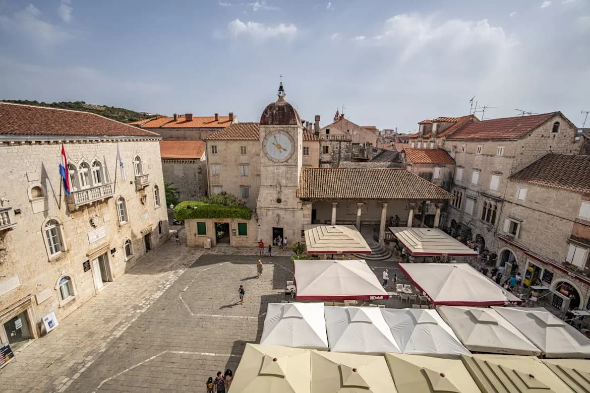 The historic bell tower of the Trogir Cathedral, a masterpiece of Romanesque architecture, rises above the city's red rooftops.