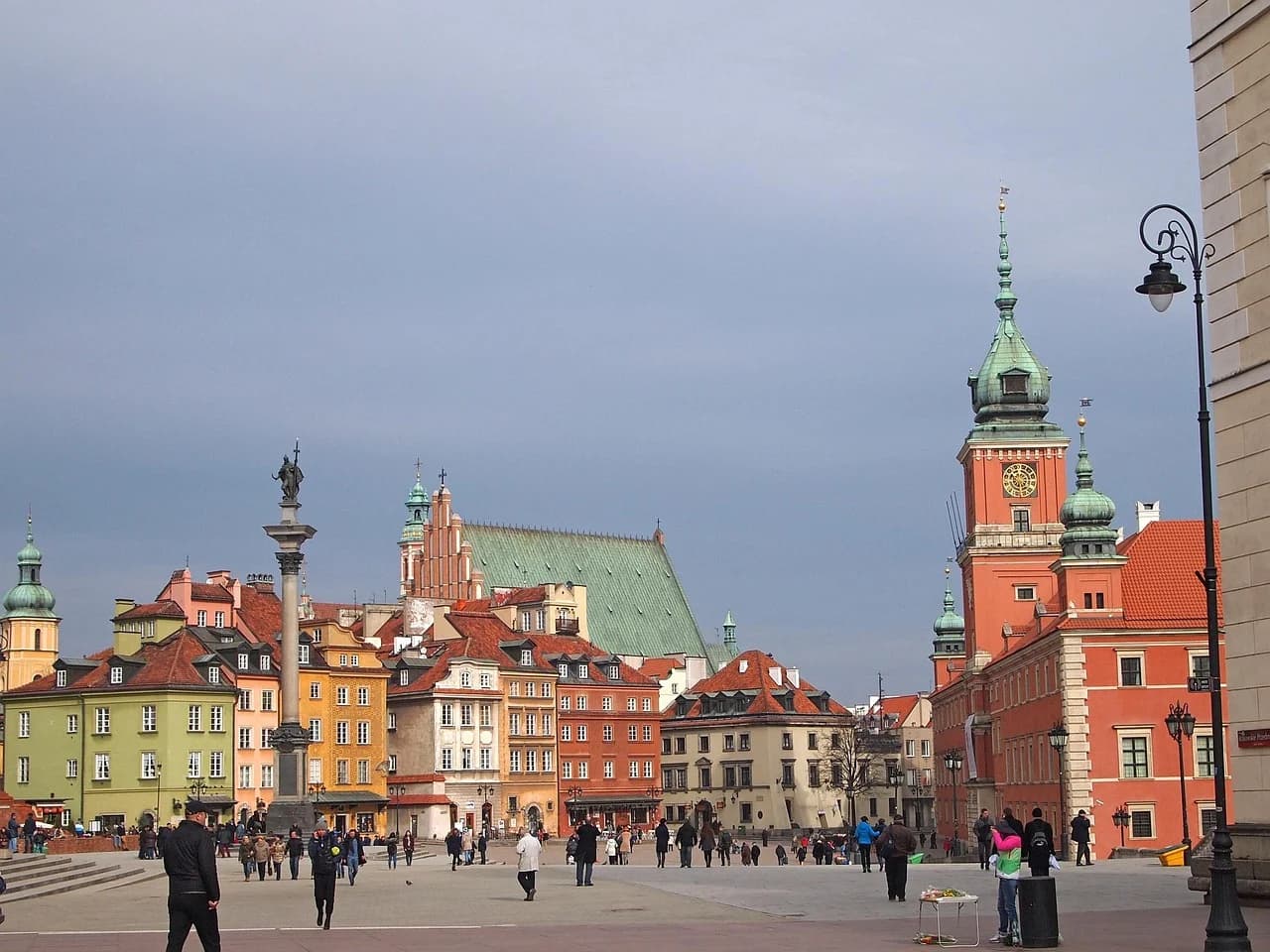 A bustling view of Warsaw's Old Town Square, showing tourists and local vendors.