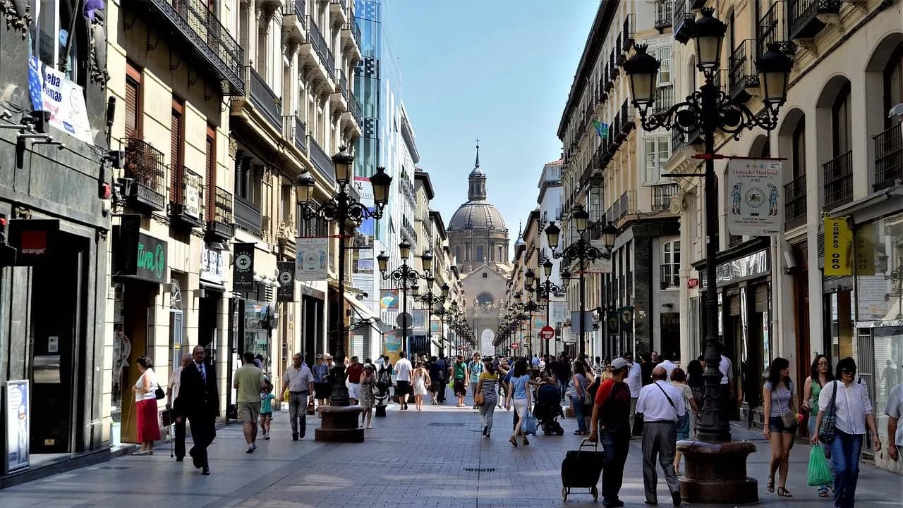 People stroll along Calle Alfonso, a vibrant shopping street leading to the stunning Basilica del Pilar in the heart of Zaragoza.